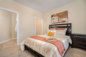 Cold Spring apartment for rent - Apartments with Attached Garage in Cold Spring, KY - Brookstone Crossing - Bedroom with Carpet Flooring, Oversized Closet, Wall Art, Nightstand, and Bed.