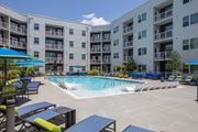 Huntsville apartment for rent - A swimming pool surrounded by lounge chairs and umbrellas in front of apartment buildings.