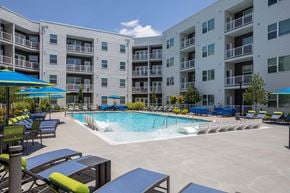Huntsville apartment for rent - A swimming pool surrounded by lounge chairs and umbrellas in front of apartment buildings.