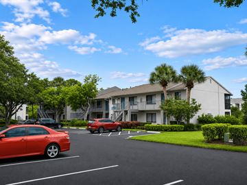 Bradenton apartment for rent - A red car is parked in a parking lot in front of a building.