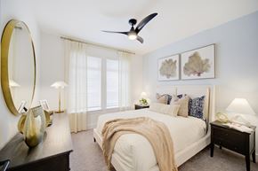Panama City Beach apartment for rent - Panama City Beach, FL, Apartments with In-Unit Washer and Dryer - Vintage Lake Powell - Bedroom With White Bed, Layered Pillows, Two Nightstands With Lamps, Ceiling Fan, And Sheer Curtains.