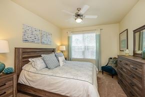 Bradenton apartment for rent - A bedroom with a bed, dresser, and ceiling fan.