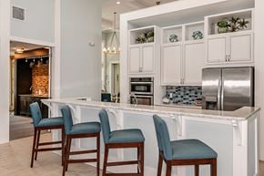 Bradenton apartment for rent - A kitchen with white cabinets and a bar area with blue chairs.