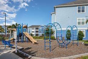 Bradenton apartment for rent - A playground with a blue slide and swings in front of a blue building.