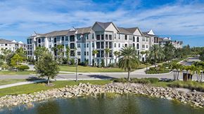 Sarasota apartment for rent - A large, modern building with a pond in front.