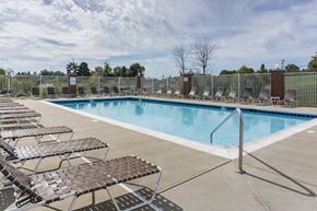 Cold Spring apartment for rent - Cold Spring, KY, Pet-Friendly Apartments - Brookstone Crossing - Outdoor Swimming Pool Surrounded by Brown Sun Loungers and a Metal Fence.