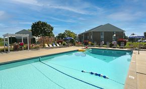 Saginaw triplex for rent - Saginaw, MI, Pet-Friendly Apartments - Waters Landing Apartments - Outdoor Swimming Pool With Wide Sundeck, Lounge Chairs, Umbrellas, Landscaping, and Apartment Buildings Under Blue Sky.