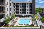 Atlanta apartment for rent - A large swimming pool is surrounded by lounge chairs and umbrellas in front of a multi-story apartment building.
