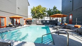 Knoxville apartment for rent - a pool with lounge chairs and umbrellas at the district flats apartments in lenexa