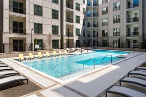 Chamblee apartment for rent - A large swimming pool surrounded by lounge chairs in front of a building.