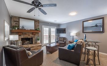 A living room with a fireplace and a ceiling fan