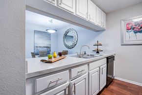 Bradenton apartment for rent - A kitchen with white cabinets and a wooden cutting board on the counter at Coral Club Apartments in Bradenton, FL