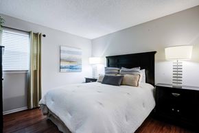 Bradenton apartment for rent - A bedroom with a large bed and a painting on the wall at Coral Club Apartments in Bradenton, FL