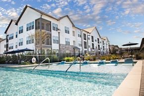 Richmond Hill apartment for rent - A swimming pool in front of a white building with blue umbrellas.