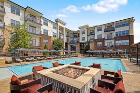 Duluth apartment for rent - A large outdoor pool surrounded by a fire pit and lounge chairs.
