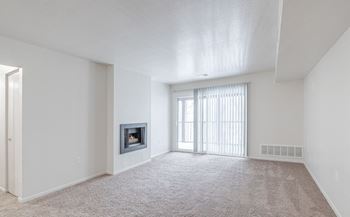 A spacious living room with a fireplace and carpeted floor