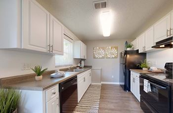 A kitchen with white cabinets and a black refrigerator
