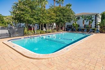 A small pool surrounded by a brick patio and trees