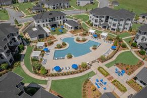 Columbus apartment for rent - A large swimming pool surrounded by blue lounge chairs and umbrellas is the centerpiece of a resort-style community.