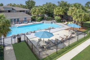 Gulf Breeze apartment for rent - A pool surrounded by chairs and umbrellas.