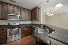 Phenix City apartment for rent - A kitchen with a stove top oven, microwave, and sink.