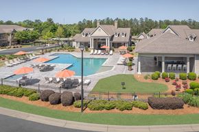 Phenix City apartment for rent - A large swimming pool surrounded by orange umbrellas and lounge chairs.