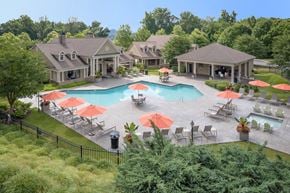 Knoxville apartment for rent - A large outdoor swimming pool surrounded by red umbrellas and lounge chairs.