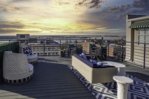 Memphis apartment for rent - a rooftop deck with furniture and a sunset over the ocean