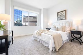 Atlanta apartment for rent - A bedroom with a large bed and a window overlooking a building.