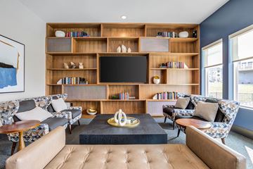 Knoxville apartment for rent - A living room with a brown leather sofa, a coffee table, and a bookshelf with a flat screen TV on top.
