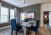 Altamonte Springs apartment for rent - Dog-Friendly Apartments in Altamonte Springs, FL - Nine12 Gateway - Dining Area with Vinyl Plank Flooring, Dining Table, Chairs, Storage Cabinet, Wall-Mounted TV, Ceiling Fan, and Large Windows.
