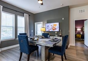 Altamonte Springs apartment for rent - Dog-Friendly Apartments in Altamonte Springs, FL - Nine12 Gateway - Dining Area with Vinyl Plank Flooring, Dining Table, Chairs, Storage Cabinet, Wall-Mounted TV, Ceiling Fan, and Large Windows.