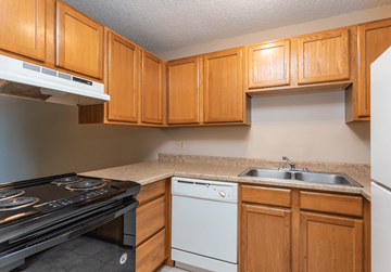 Colorado Springs apartment for rent - A kitchen with wooden cabinets and a black stove top oven.