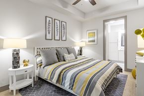 Atlanta apartment for rent - Midtown Atlanta, GA Luxury Apartments with In-Unit Washer and Dryer - Trace Midtown - Bedroom with Carpet Flooring, Area Rug, Large Bed, Nightstands with Lamps, Dresser, Ceiling Fan, and Attached Bathroom.