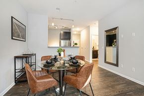 Grand Rapids apartment for rent - Grand Rapids, MI, Apartments with In-Unit Washer and Dryer - Knapp’s Corner Flats - Dining Area With Round Glass Table, Brown Upholstered Chairs, Wood Style Flooring, And Open View Into Kitchen.