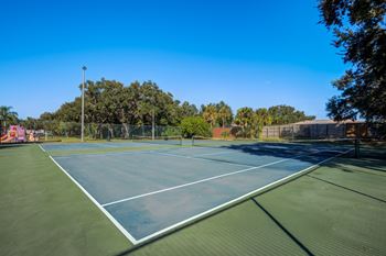 A tennis court surrounded by trees and a fence