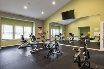A gym with a row of treadmills and exercise bikes