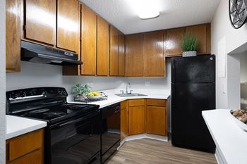 A black refrigerator is in a kitchen with wooden cabinets
