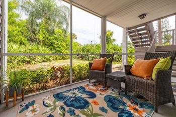 A patio with a couch, chairs and a rug