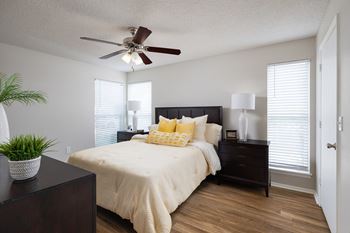 A bedroom with a bed, nightstand, and a plant