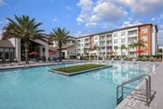 Daytona Beach apartment for rent - A large swimming pool in front of a multi-story apartment building.