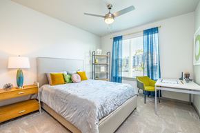 Daytona Beach apartment for rent - Pet-Friendly Apartments In Daytona Beach, FL - Madison Pointe - Bedroom With Bookshelf, Desk, Chair, Nightstand, Bed, Ceiling Fan, And Large Window.