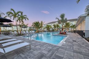 Port St. Lucie apartment for rent - A pool surrounded by palm trees and lounge chairs.