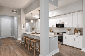 Sunrise apartment for rent - A kitchen with white cabinets and a bar area with stools.