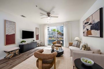 Tampa apartment for rent - A living room with a television, a chair, a sofa, and a table with a bowl of salad on it.
