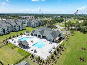 Fort Walton Beach apartment for rent - A large swimming pool is surrounded by a grassy area and a few buildings.