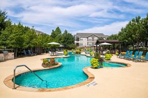 Little Elm apartment for rent - a swimming pool with lounge chairs and umbrellas with a house in the background at Orion McCord Park, Little Elm, TX, 75068