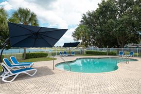 Avon Park apartment for rent - a resort style pool with chaise lounge chairs and umbrellas