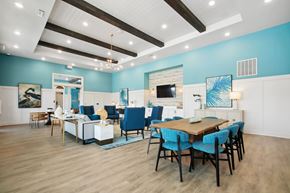 Flagler Beach apartment for rent - Luxury Apartments for Rent in Flagler Beach, FL - Preserve at Flagler Beach - Resident Lounge With Blue Accent Walls, Dining Table, Sofa Seating, High Ceilings, Wood Beams, And Wood Style Flooring.