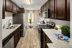 Sandy Springs apartment for rent - A kitchen with dark wood cabinets and a granite countertop.